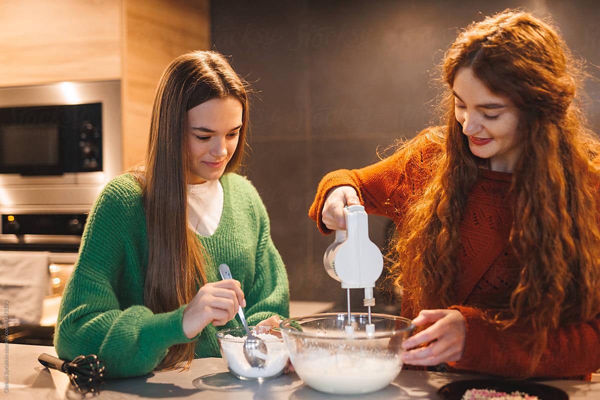 Young female teen helping to sister preparing icing