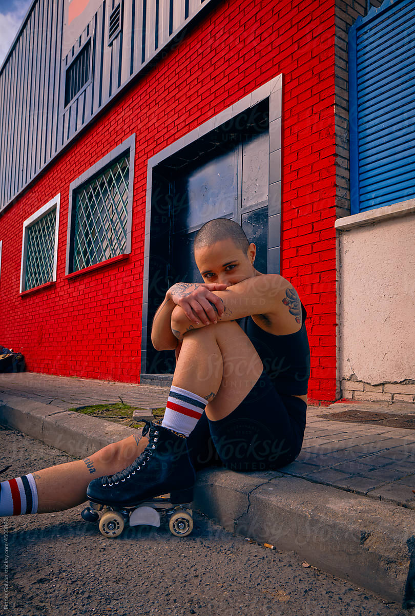 Urban portrait of a roller skater posing with their arms covering face