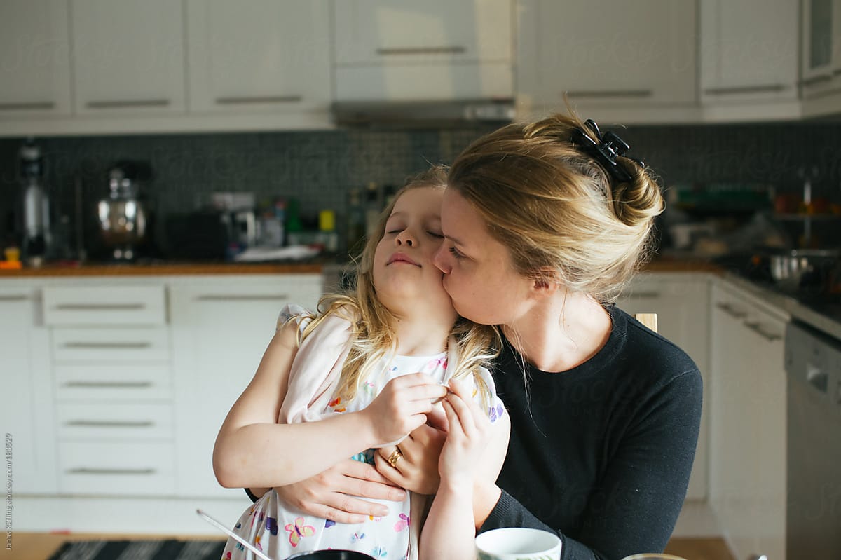 Mother Giving Her Daughter A Good Morning Kiss At The Breakfast Table by Jo...