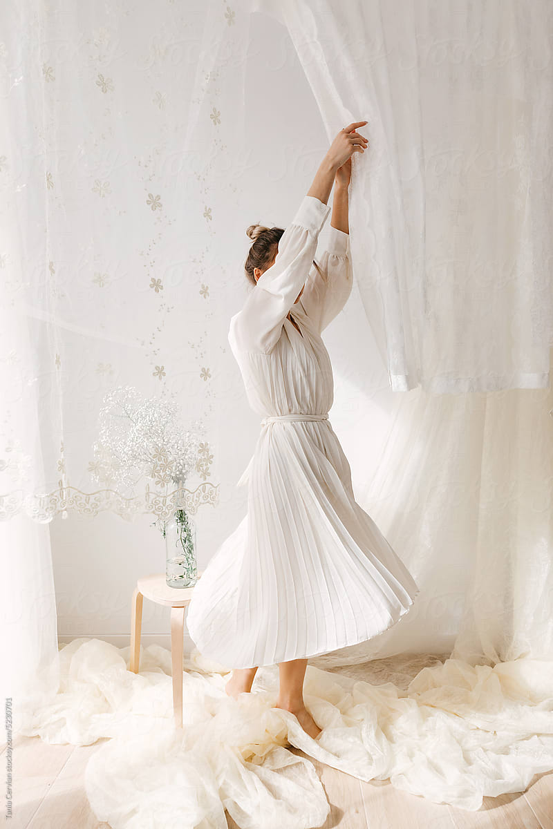 Carefree woman dancing in light dress in studio