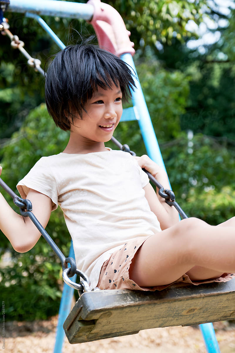 Asian little girl swinging in a lovely public small park in Japan