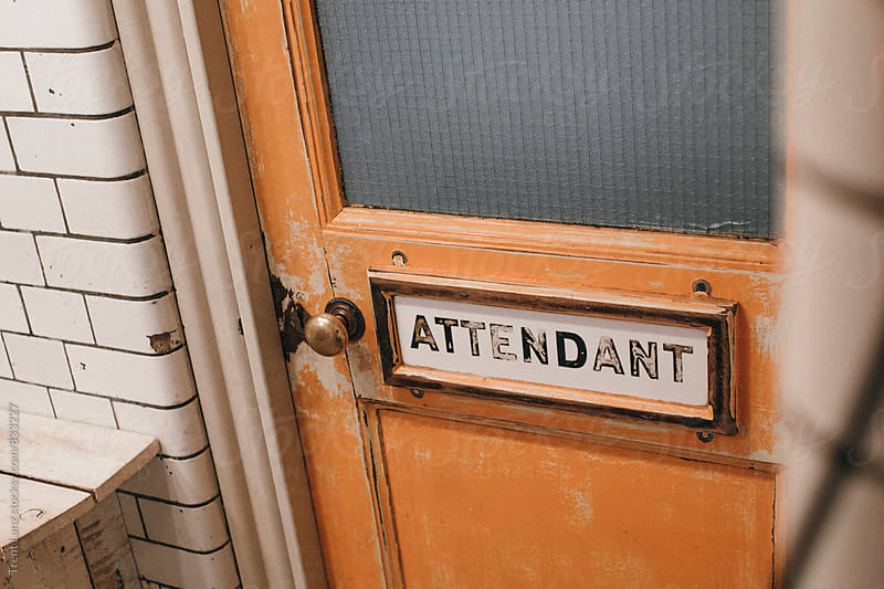 Shabby orange stall door with bathroom \'attendant\' door-plate