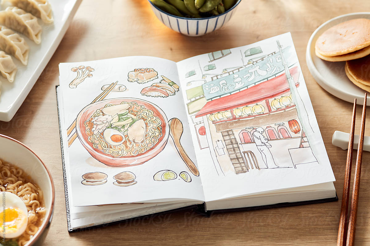 Opened sketchbook with watercolor drawing of Japanese food and cafe