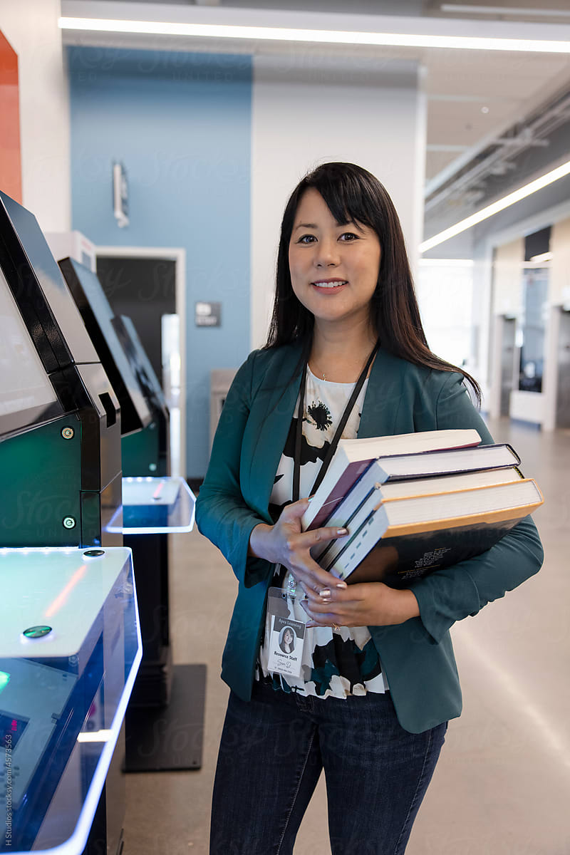 Portrait confident female librarian with books at self checkout