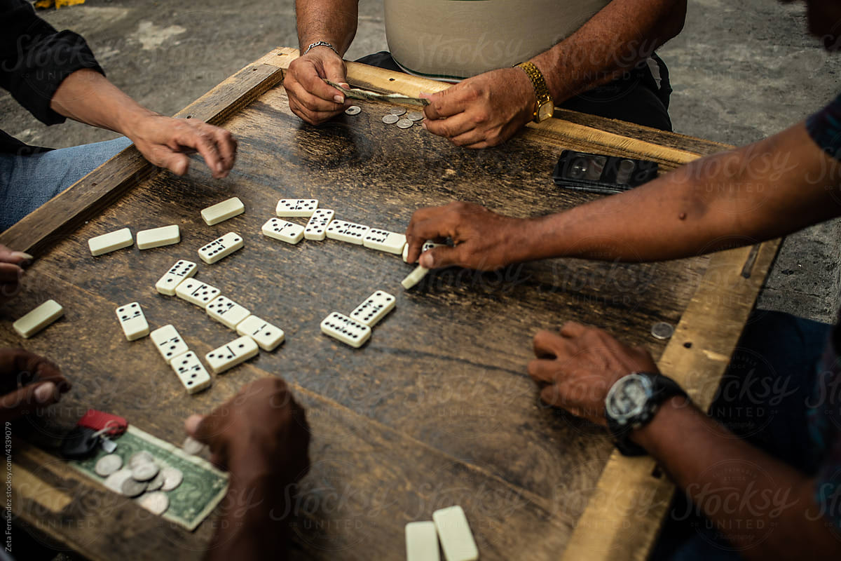 friends playing dominoes on a wooden table.