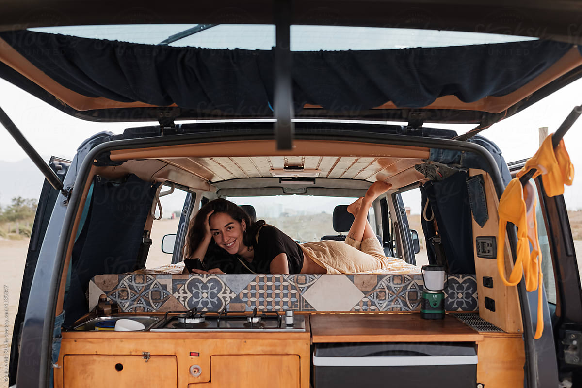 Young woman relaxes inside camper van
