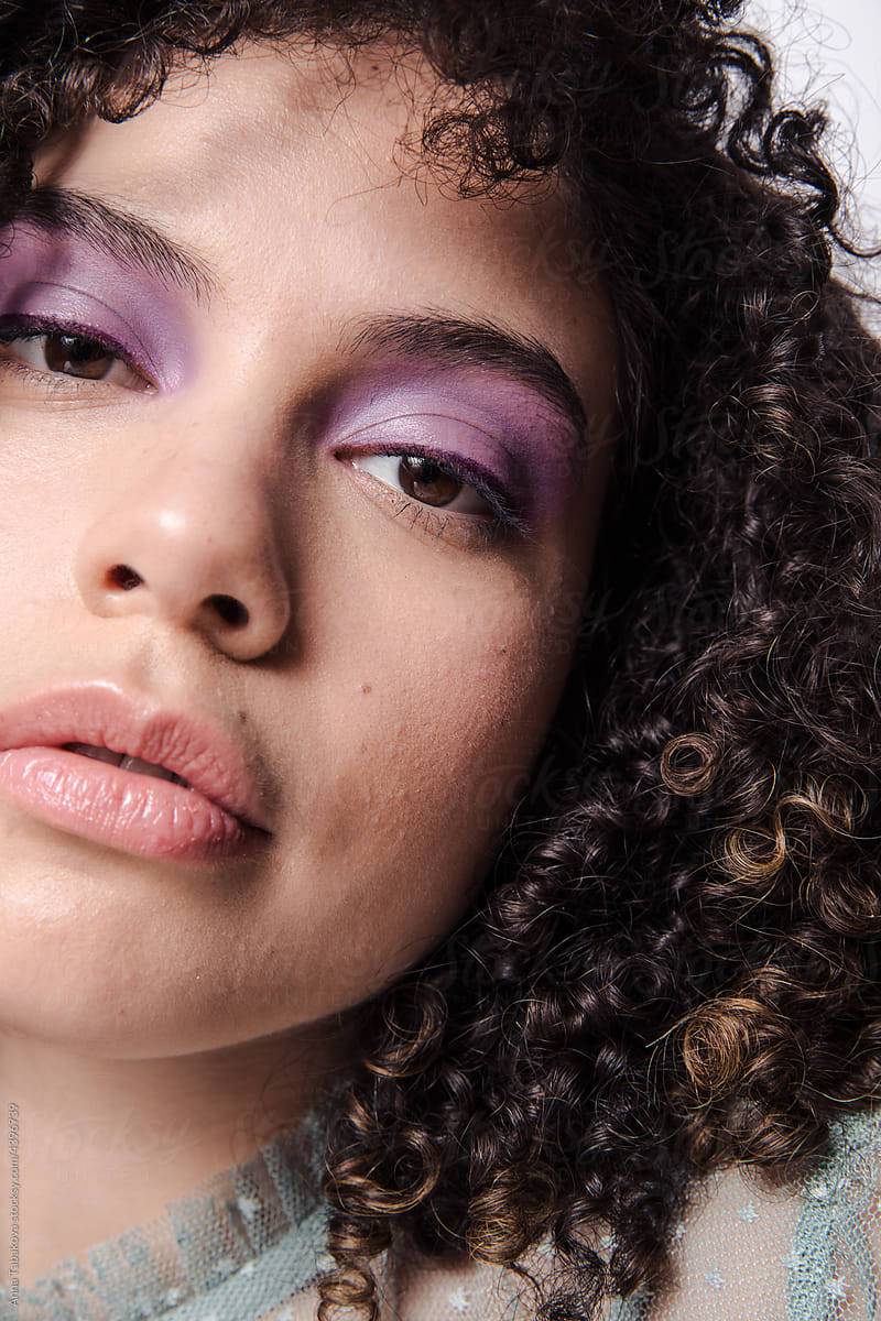 Model with  curly afro hair and purple makeup