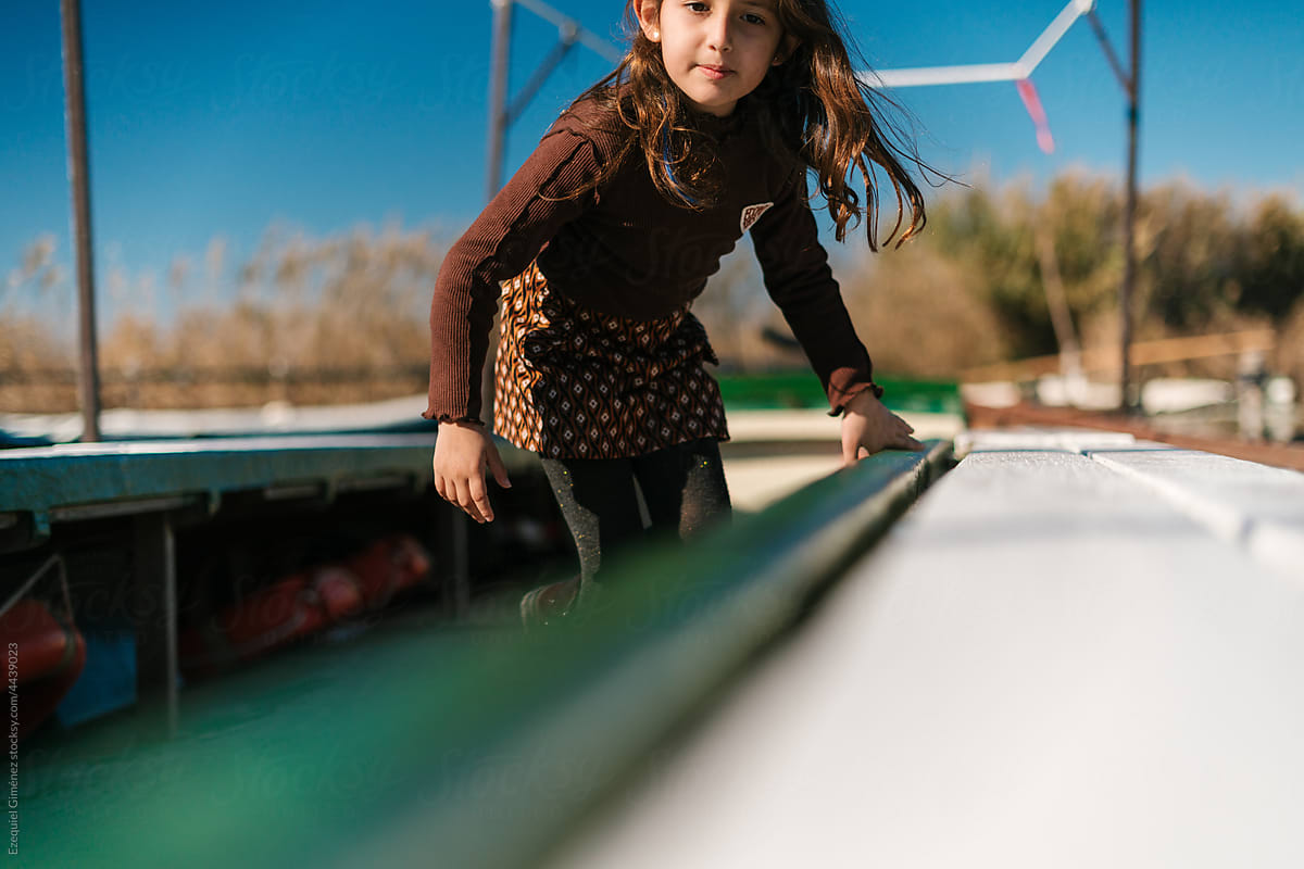 Adorable girl in wooden boat on lake