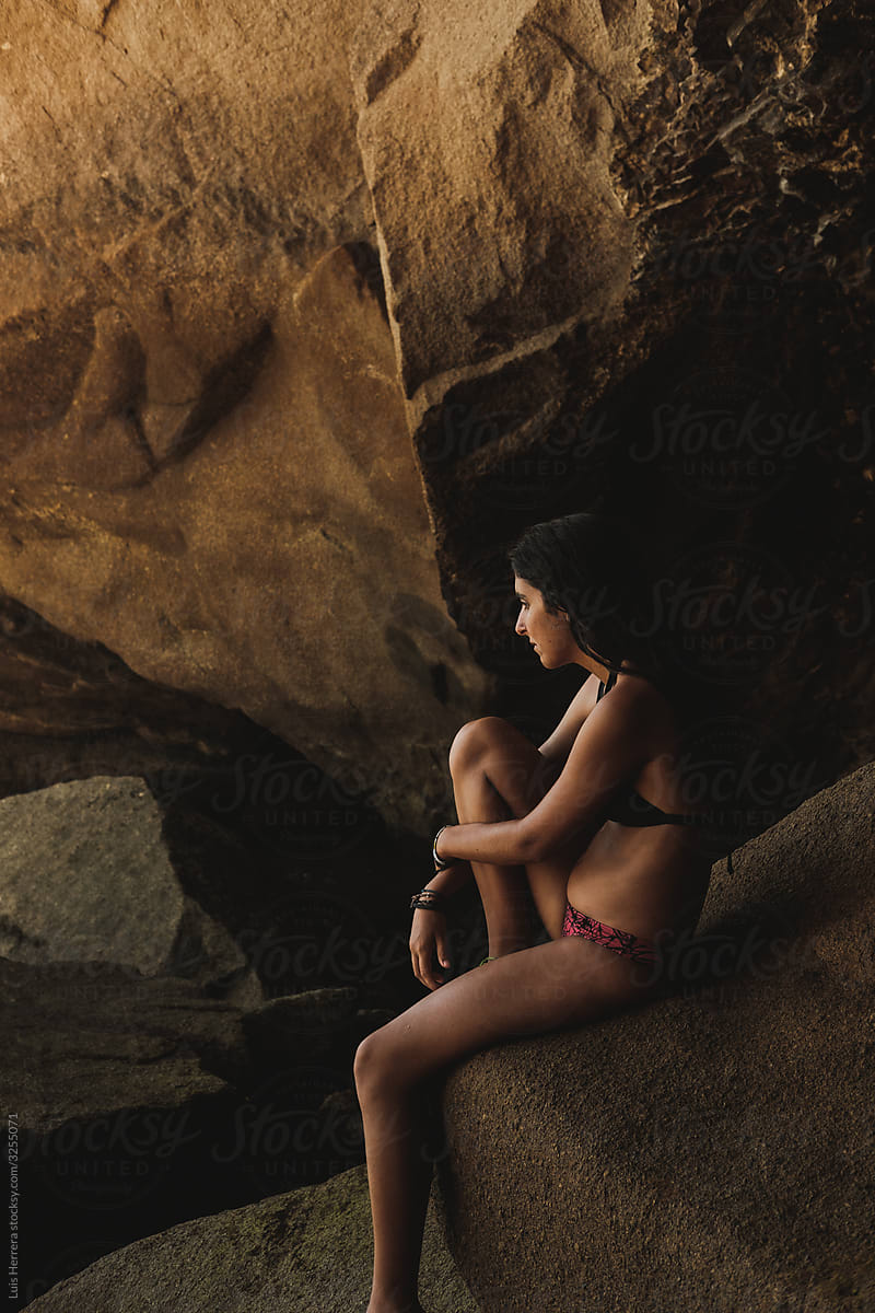 woman with sitting in a big rock inside a cave