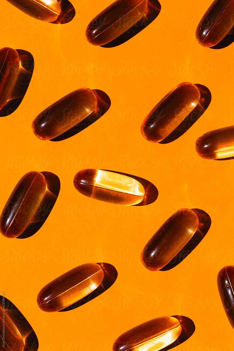 Golden omega 3 capsules on a light orange background