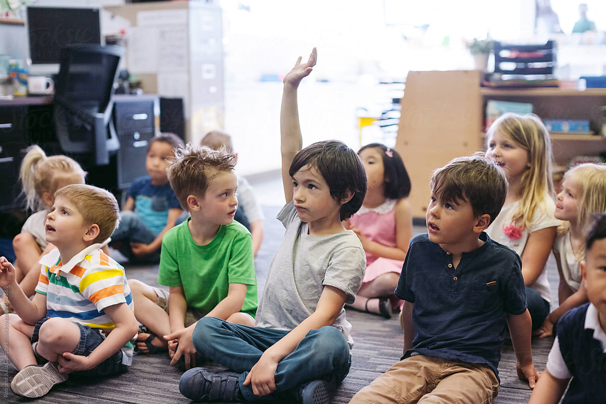 Kindergarten kid raising hand in classroom