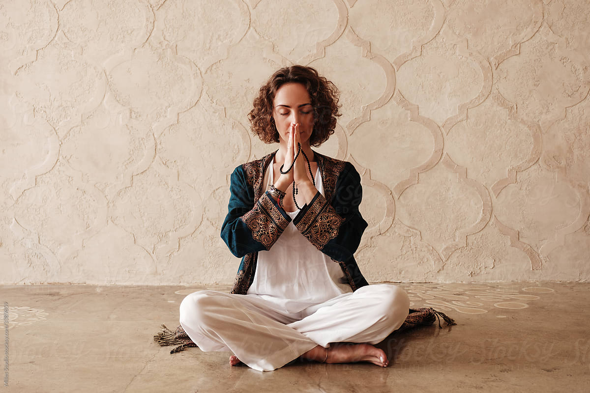Barefoot woman meditating with beads in clasped hands
