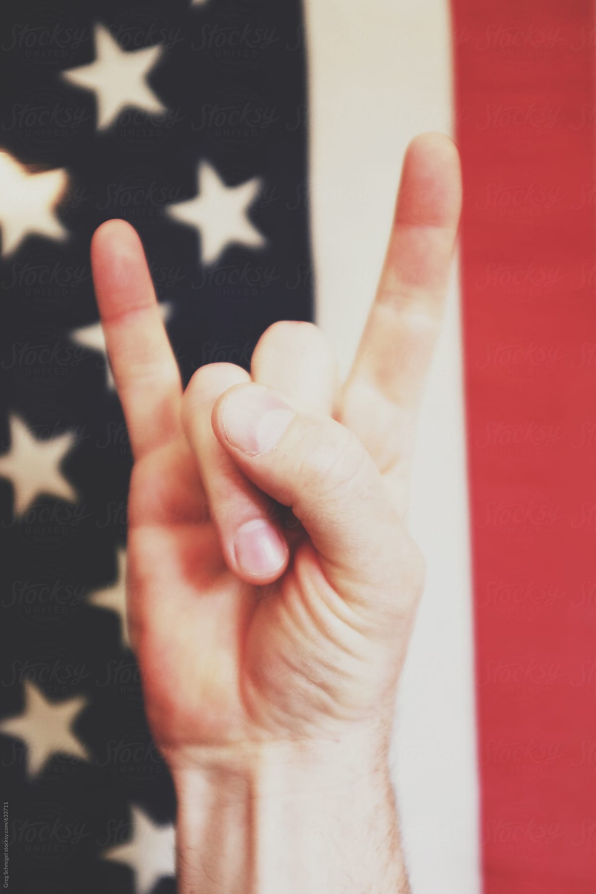 Rock and roll hand and finger gestures in front of an old American Flag