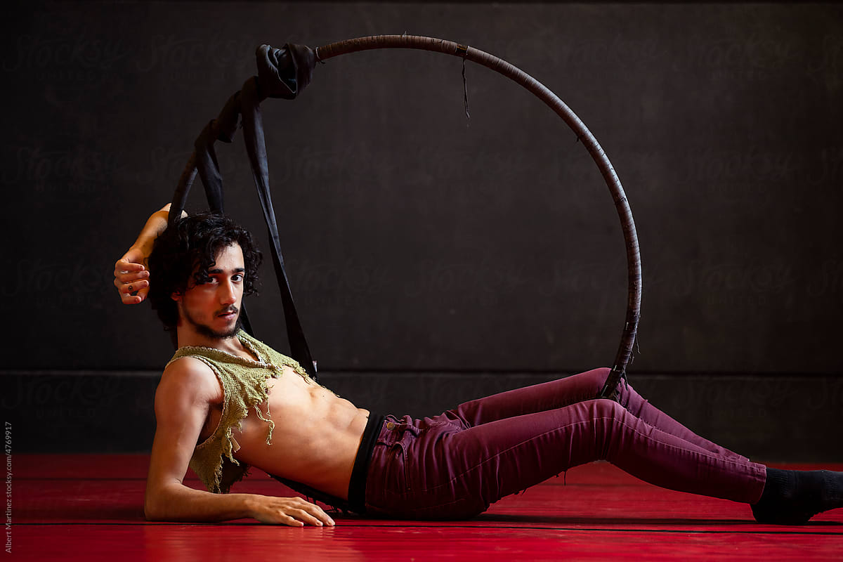 Charismatic male circus artist with hoop lying on floor