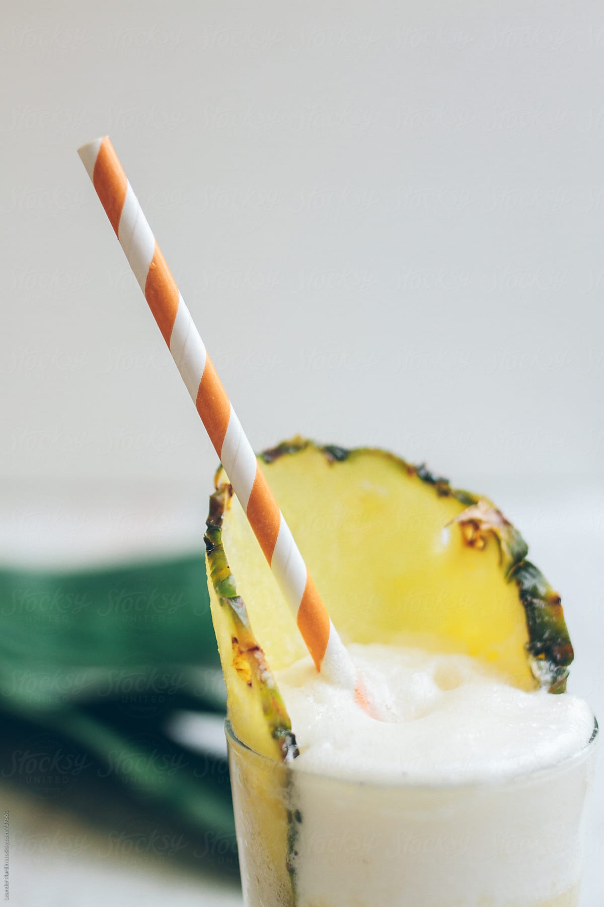 close up of a pina colada cocktail with a pineapple garnish and colorful drinking straw
