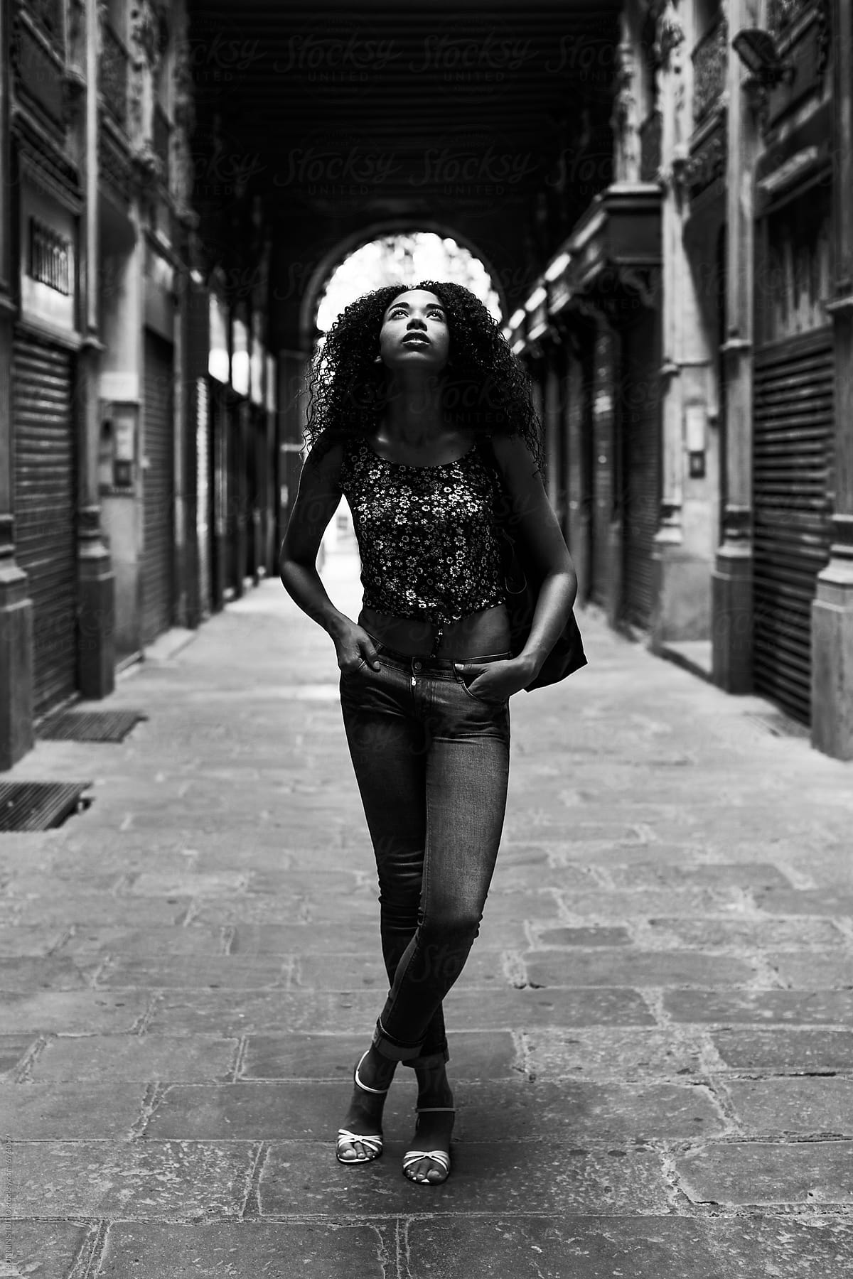 Young latin woman looking up standing on the street. Black and white photo.