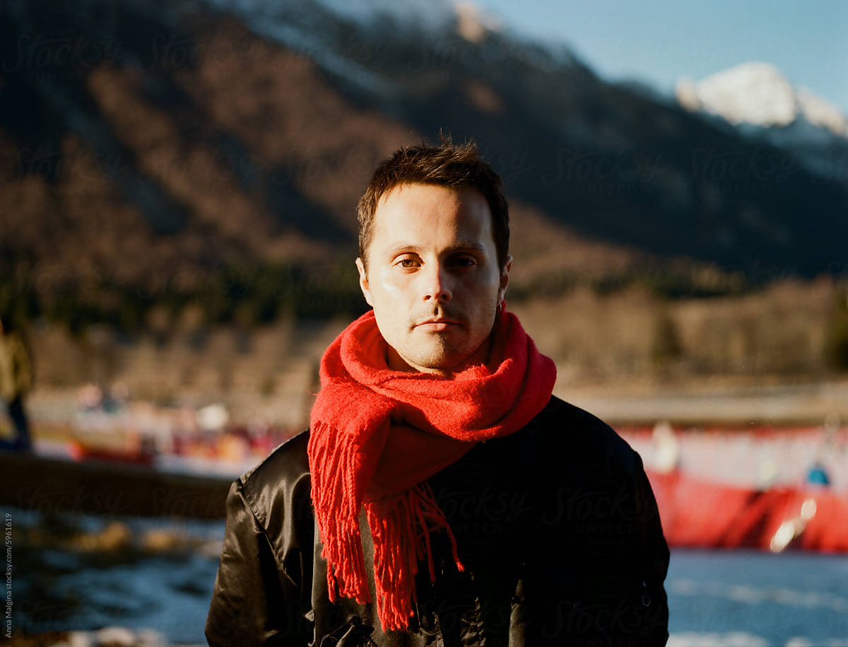 Man in Red Scarf Standing in Winter Landscape at Dusk