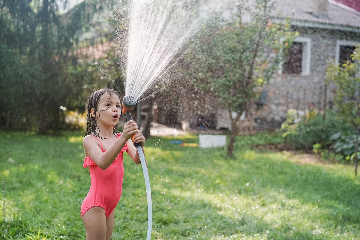 Little girl having fun with garden hose