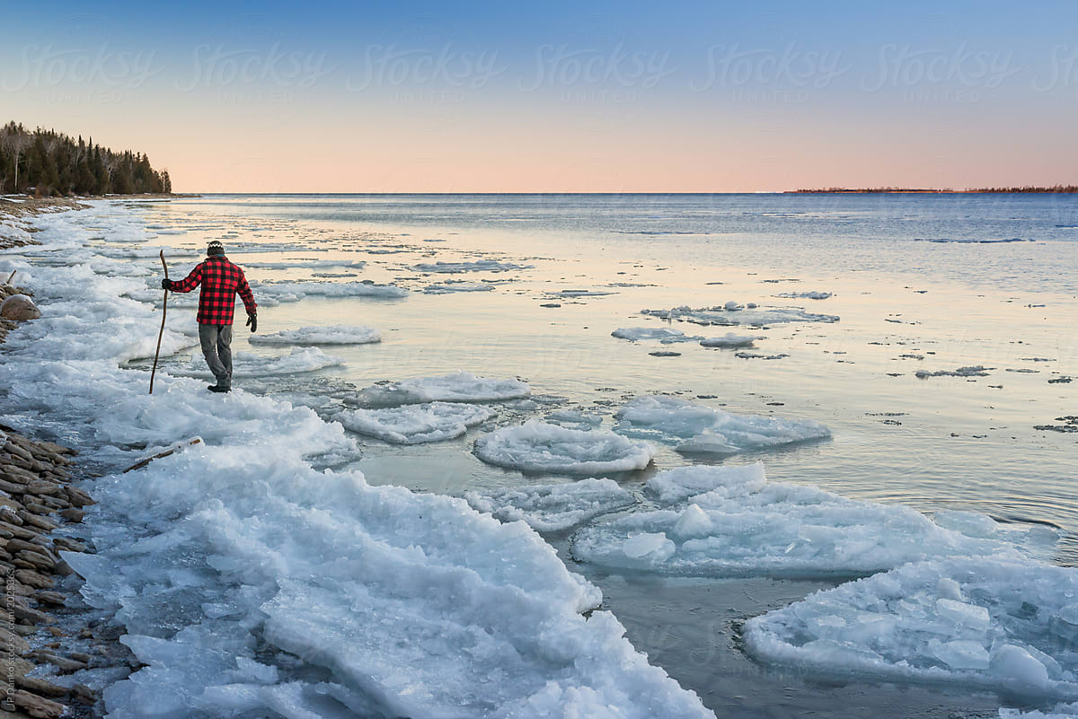 Solitary man walks along icy shoreline of Ontario lake