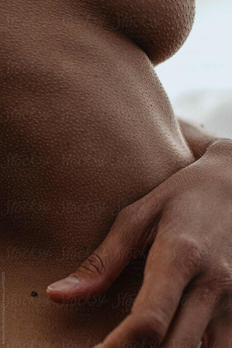Close up vertical photo of naked woman's skin texture with the hand