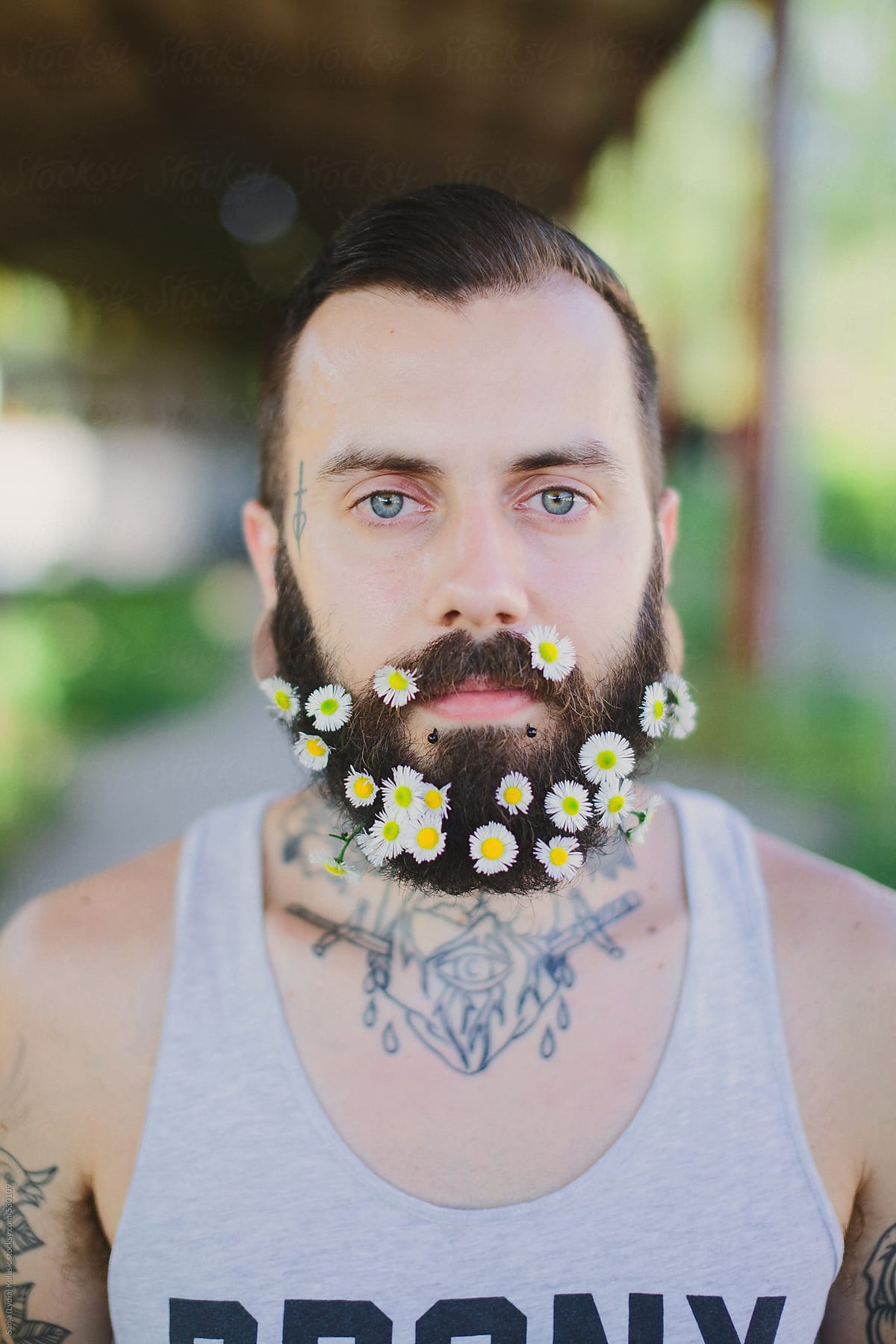 Young blue eyed tattooed man with floral beard