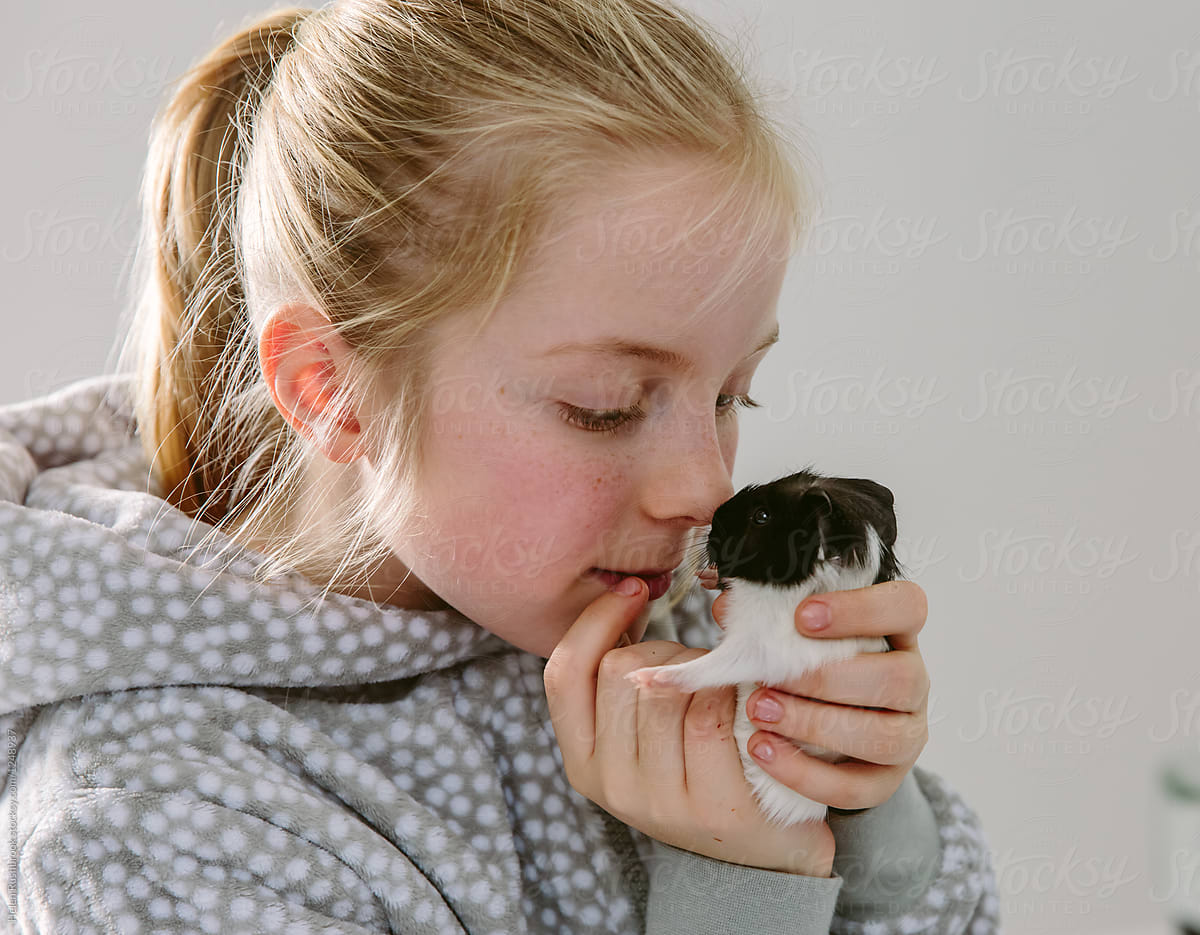 little girl rubbing noses with a baby guinea pig