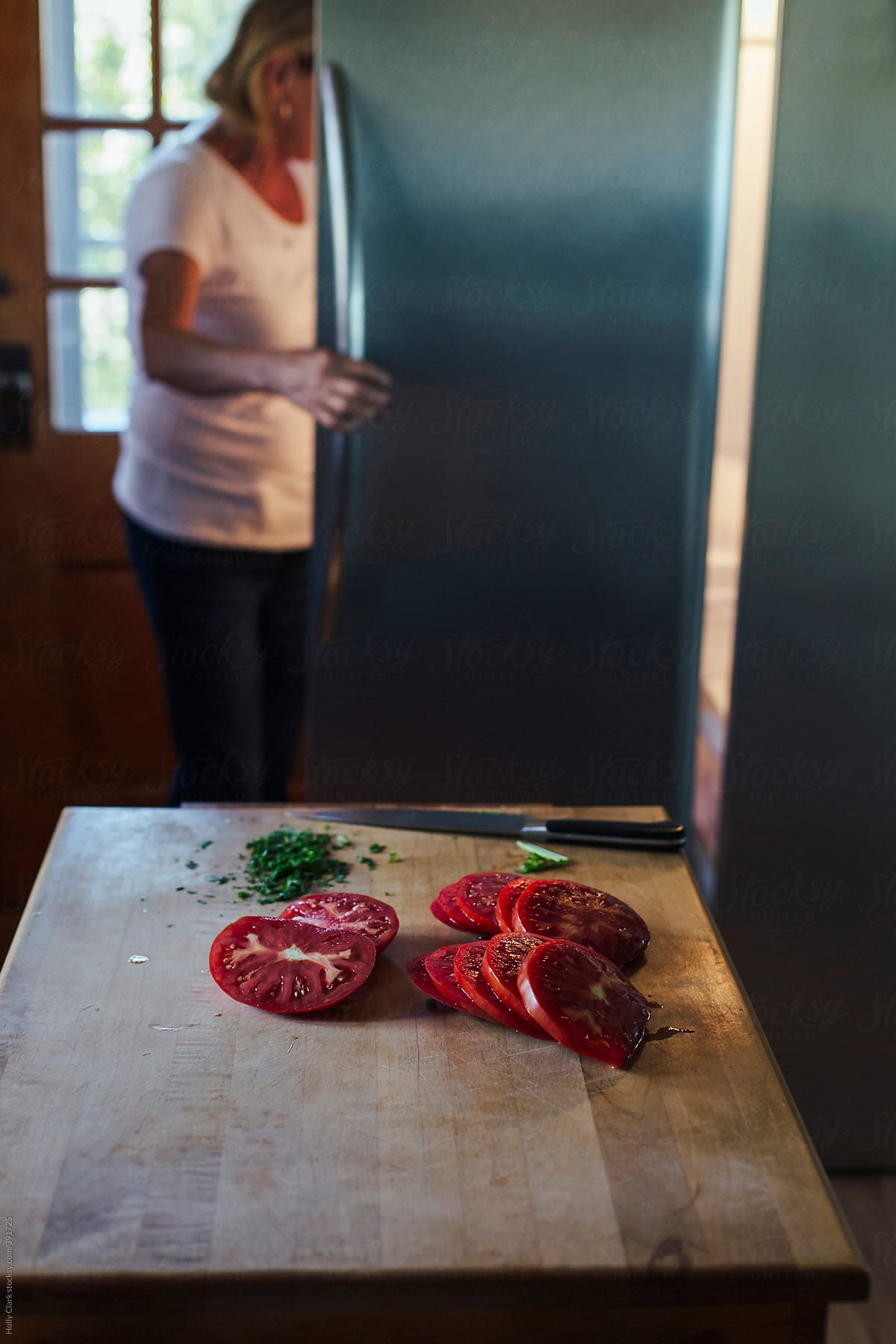 A woman looks inside refrigerator in kitchen