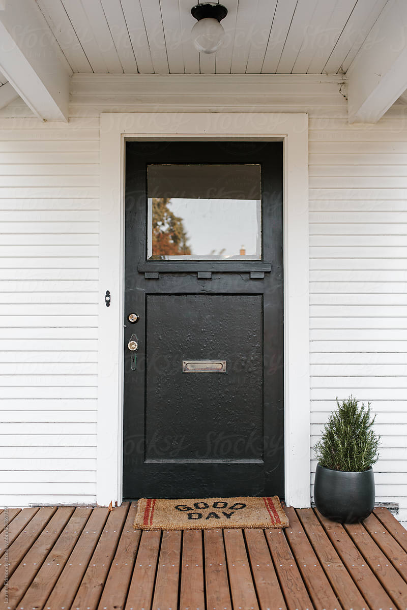 Black, textured front door with welcome mat