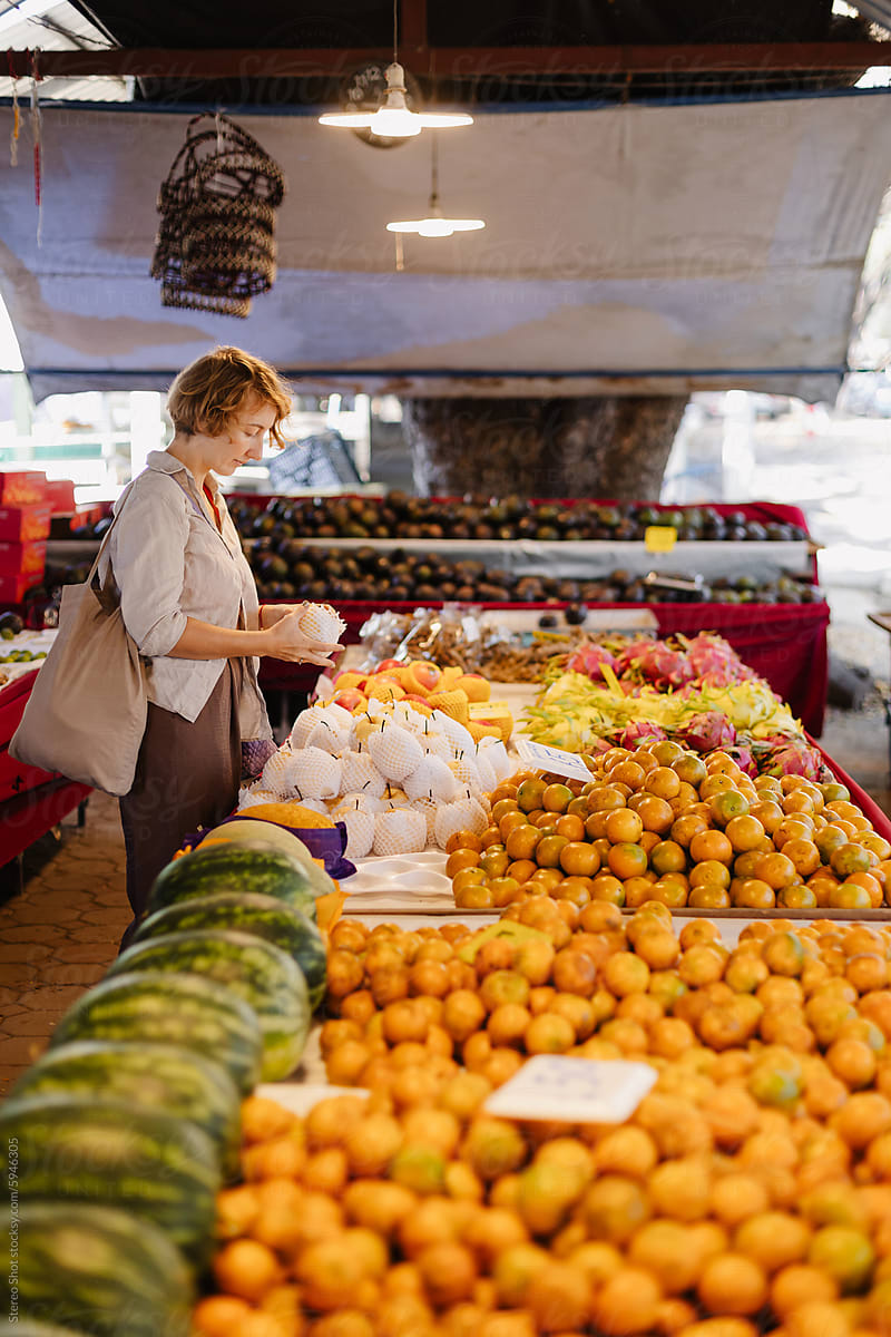 Young woman choosing fruits in farmer asian market