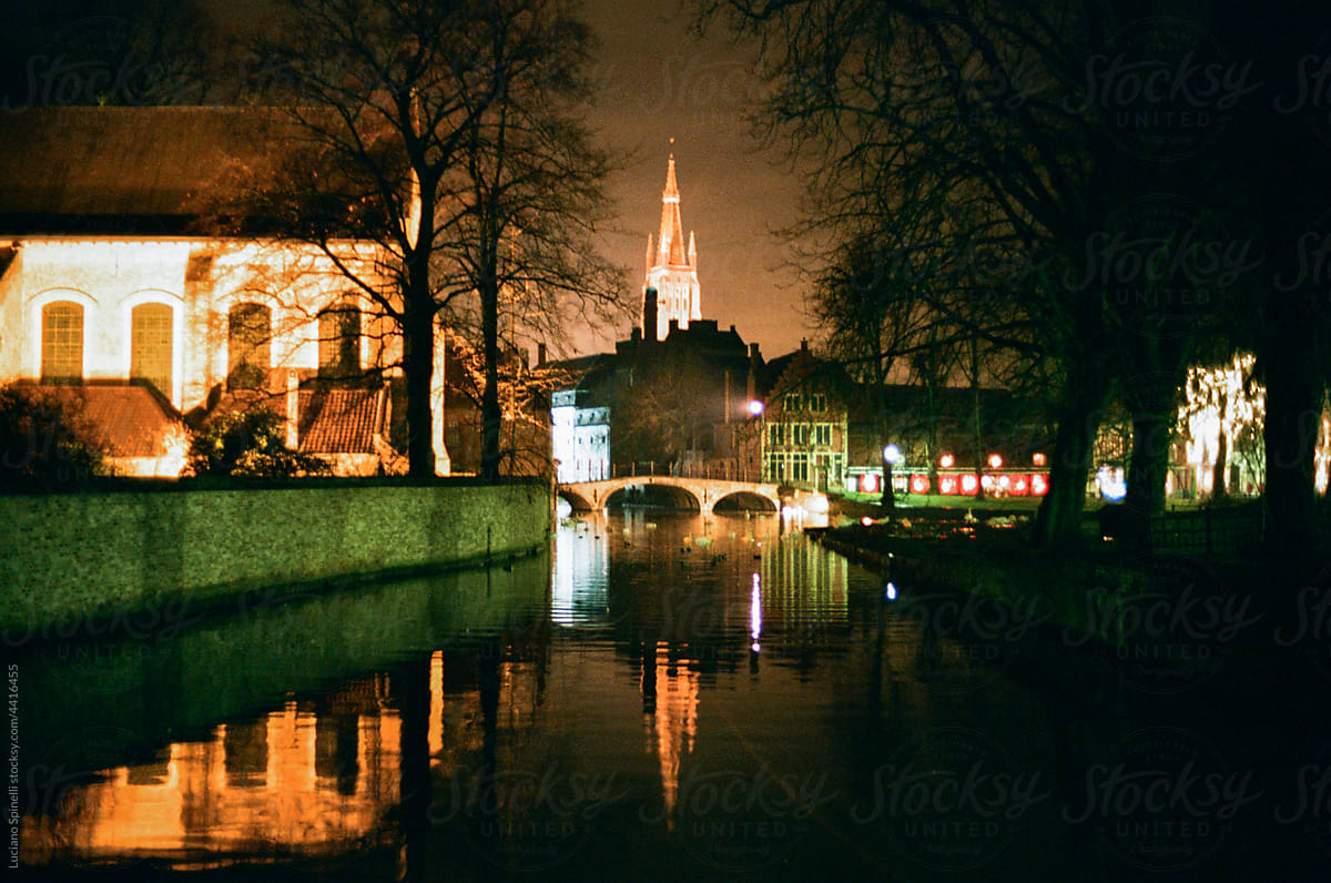 The canals of Bruges by night with a church and a bridge