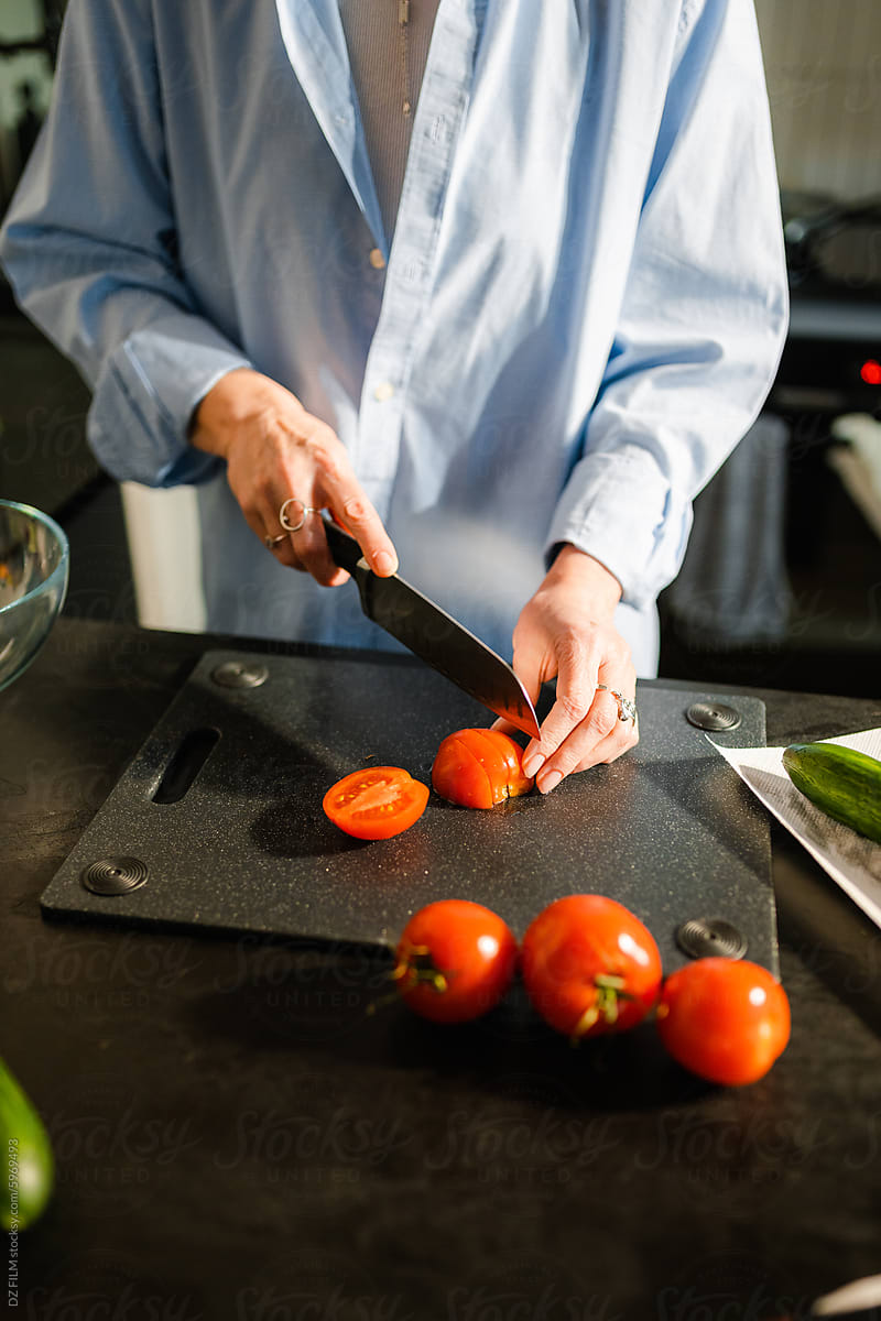 A woman is slicing tomatoes