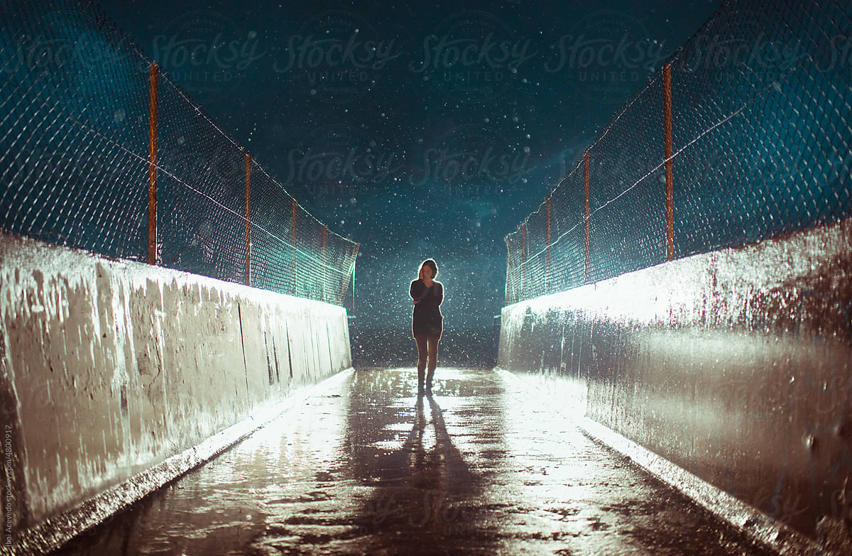 Standing woman under heavy rain at night
