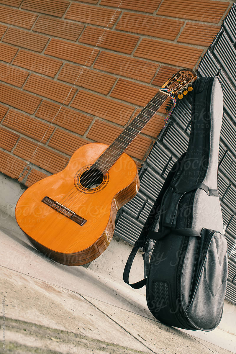 Classic guitar on black case leaning against brick wall