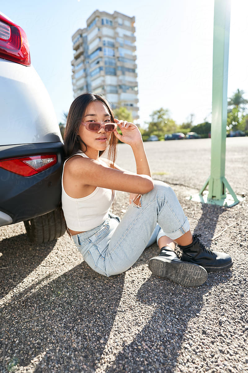 Stylish woman sitting near car