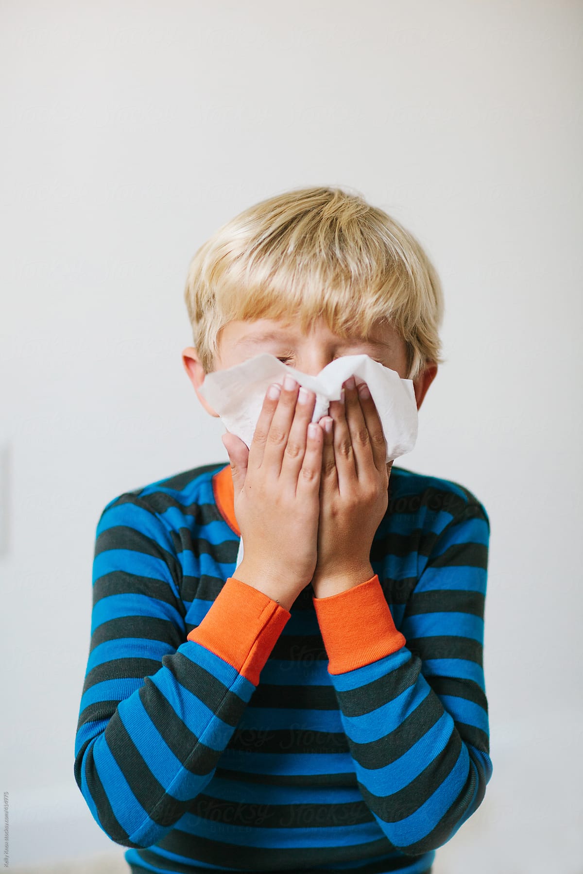 sick child blowing his nose into a tissue