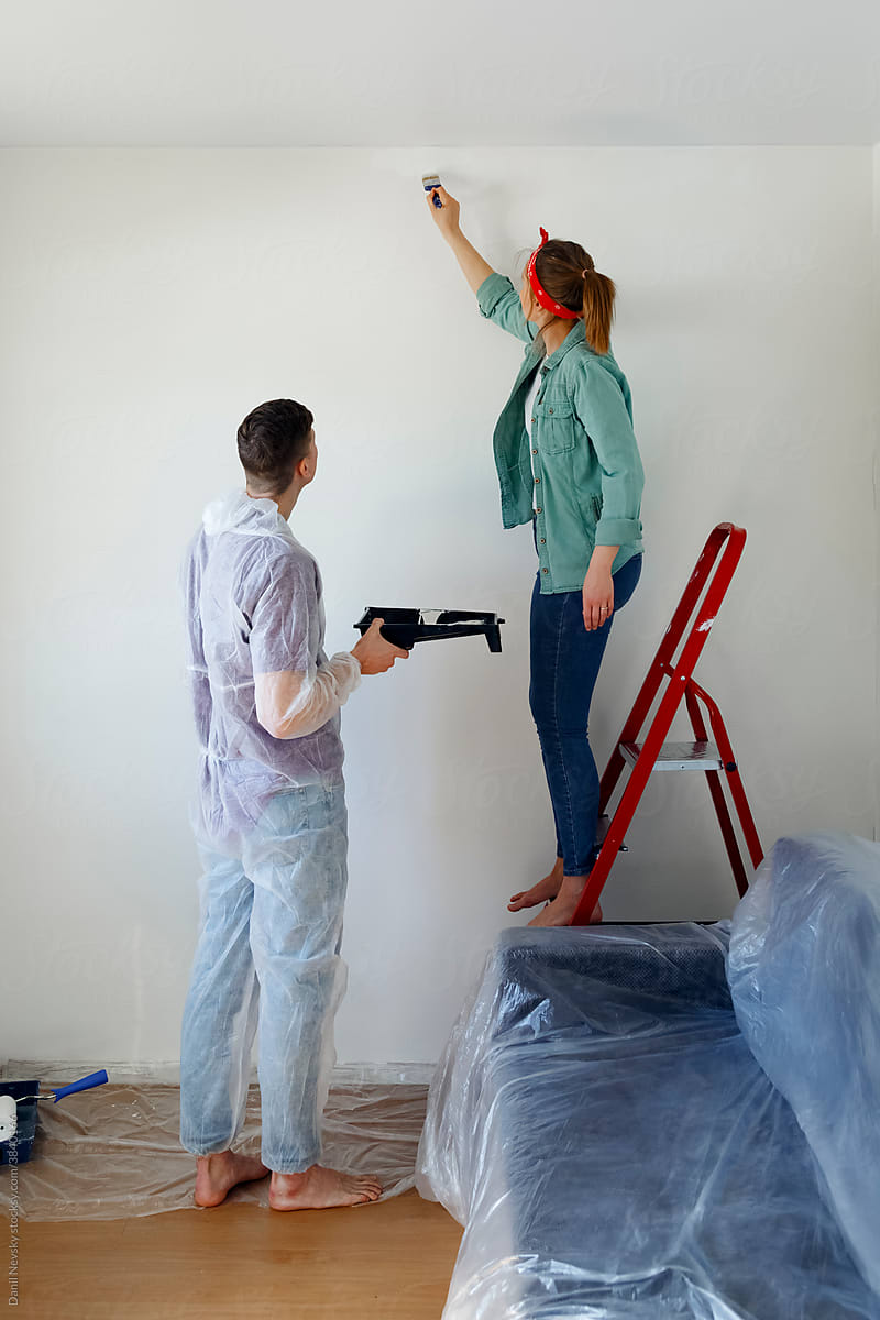 Husband and wife painting wall in living room