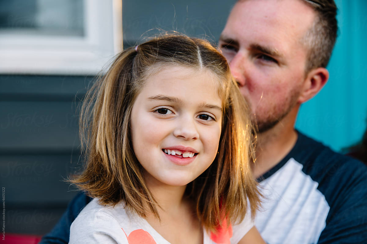 Young girl smiles at camera with dad behind her