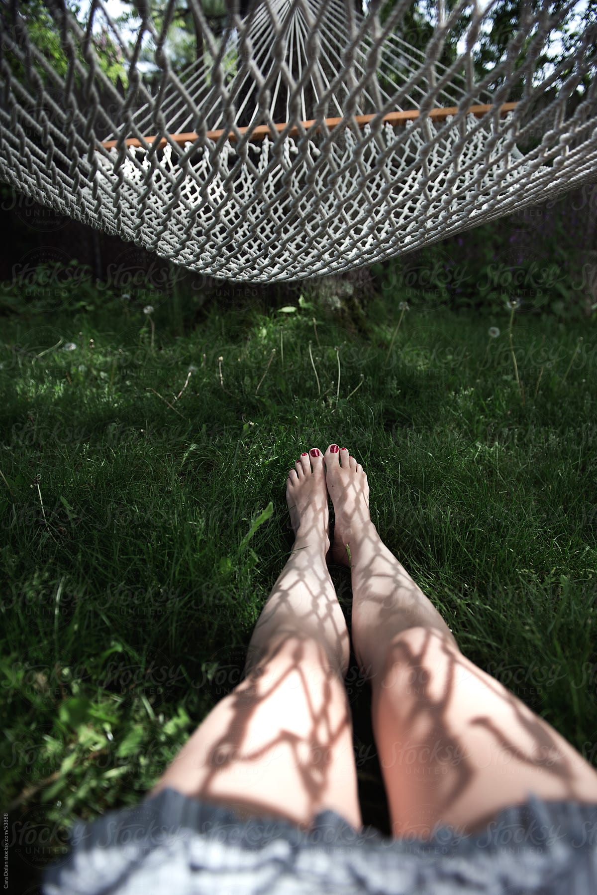 Woman lies on the grass under a hammock