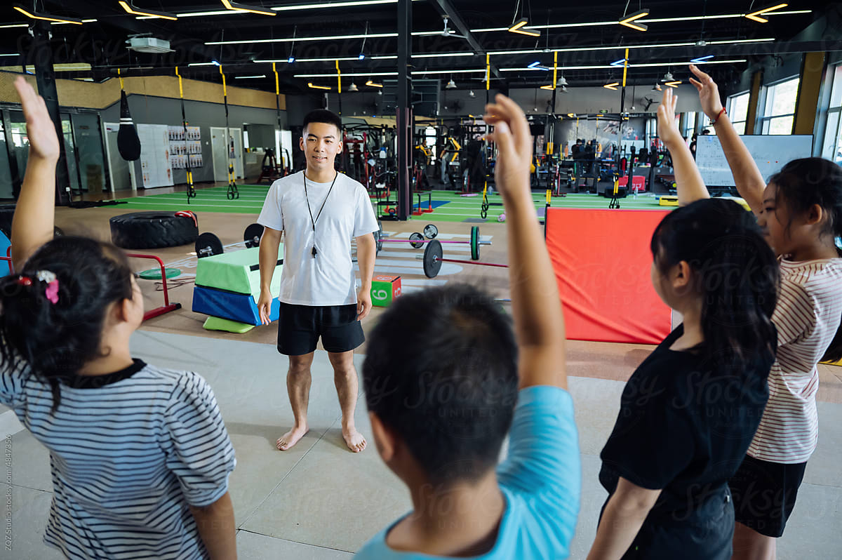 Asian coach teaching young kids