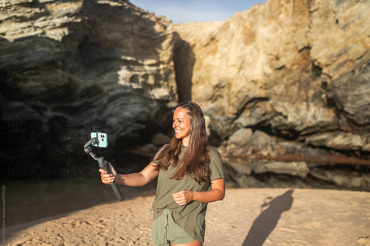 videographer woman using mobile phone with gimbal in nature