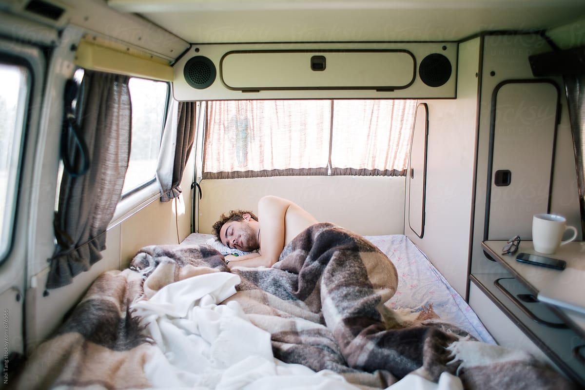 Young man sleeping in old camper van