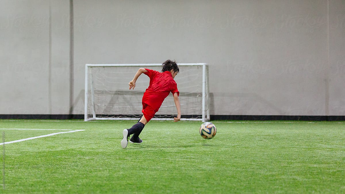 Young male football player practicing in an indoor football facility