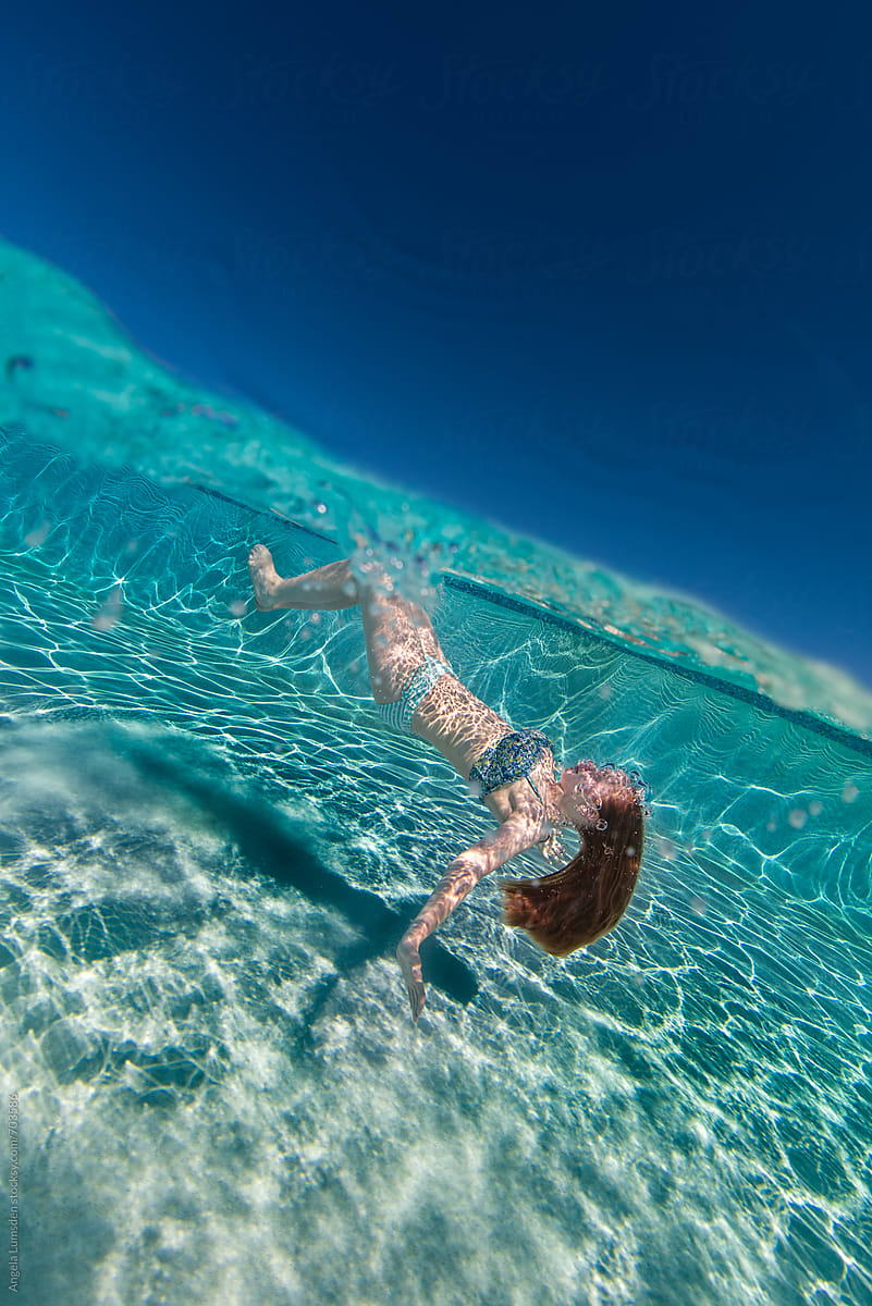 Over Under Image Of A Girl Floating Upside Down Under Water In A