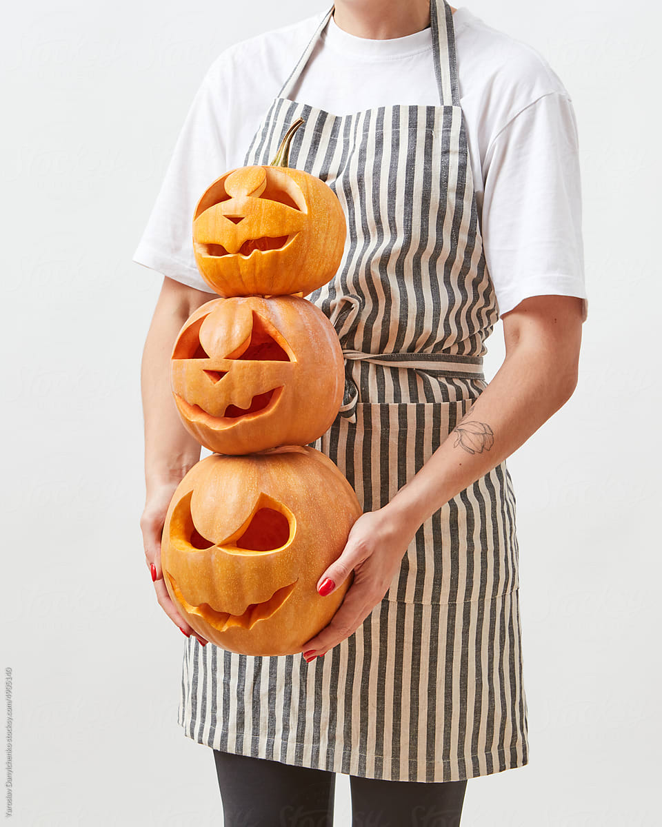 Pumpkins with Halloween carving held by woman.
