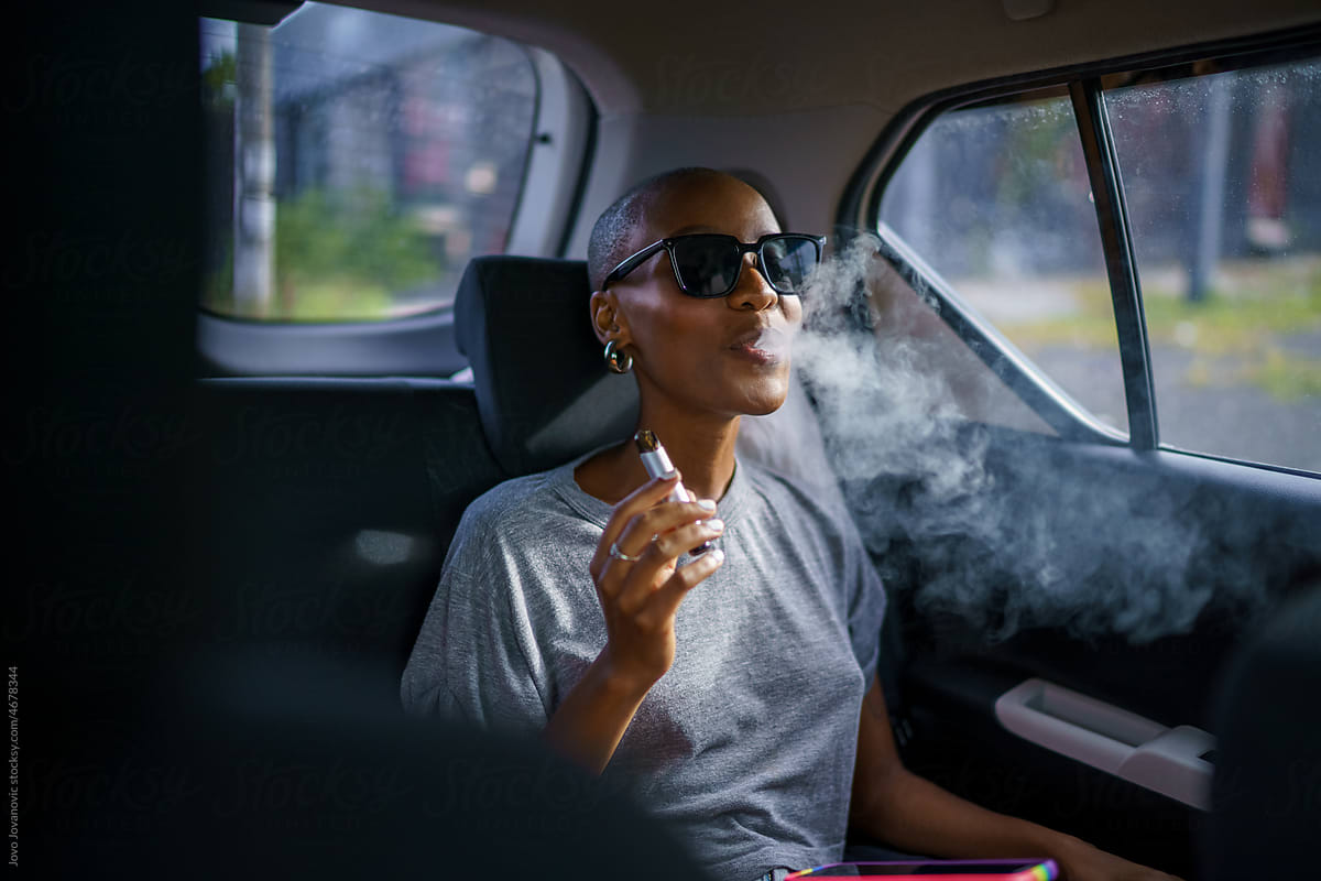 Young black woman vaping in back of car
