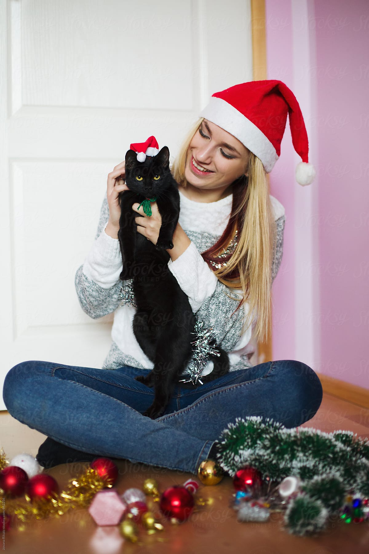 Beautiful young woman and her cat wearing Santa hats