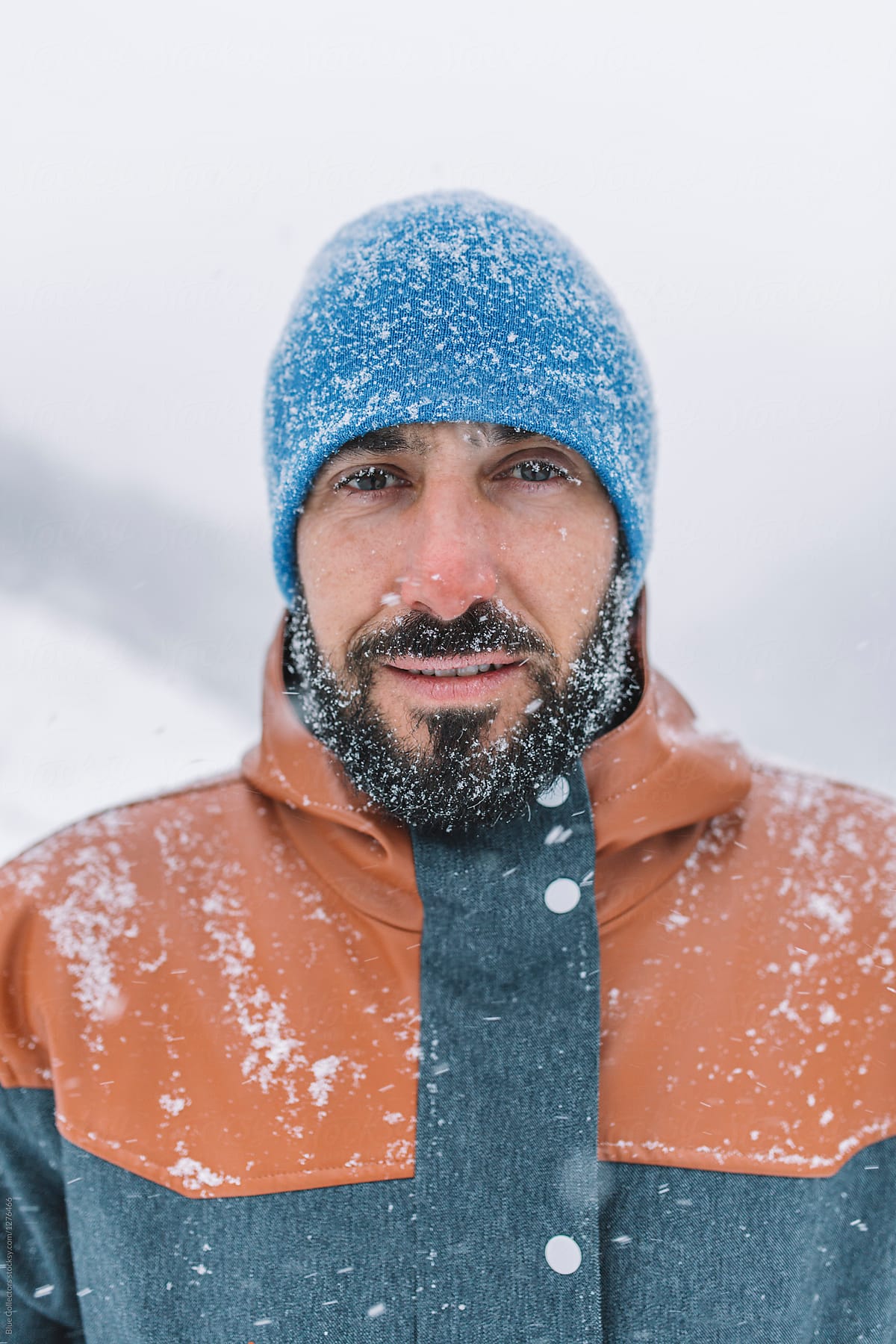 portrait of bearded man covered with snow walking in a snowy road at hard winter day