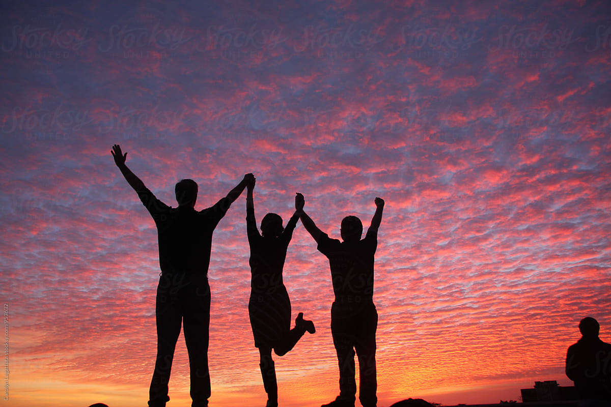 People With Their Arms Raised In Celebration With A Vibrant, Pink Sky by Stocksy  Contributor Carolyn Lagattuta - Stocksy