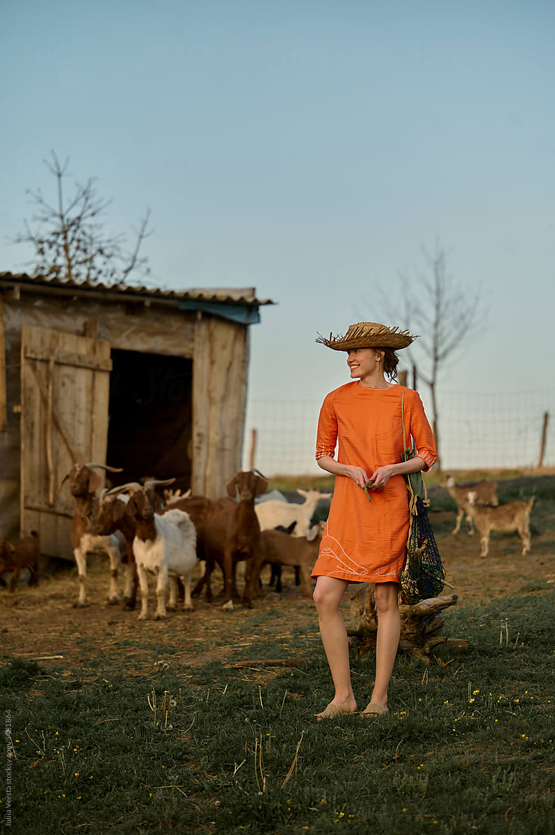 woman in a straw hat with the goats on background