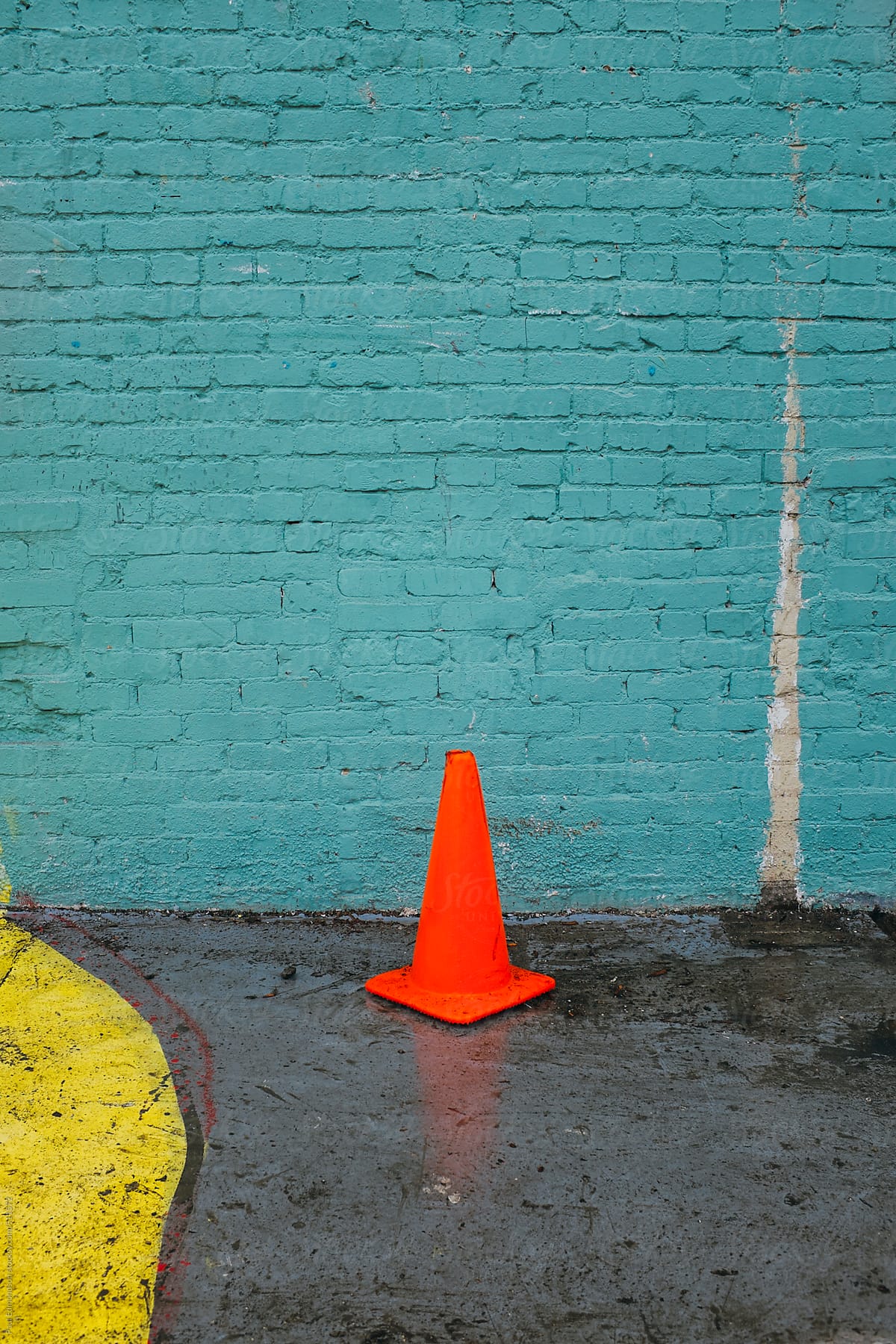 Traffic cone in front of colorfully painted brick wall